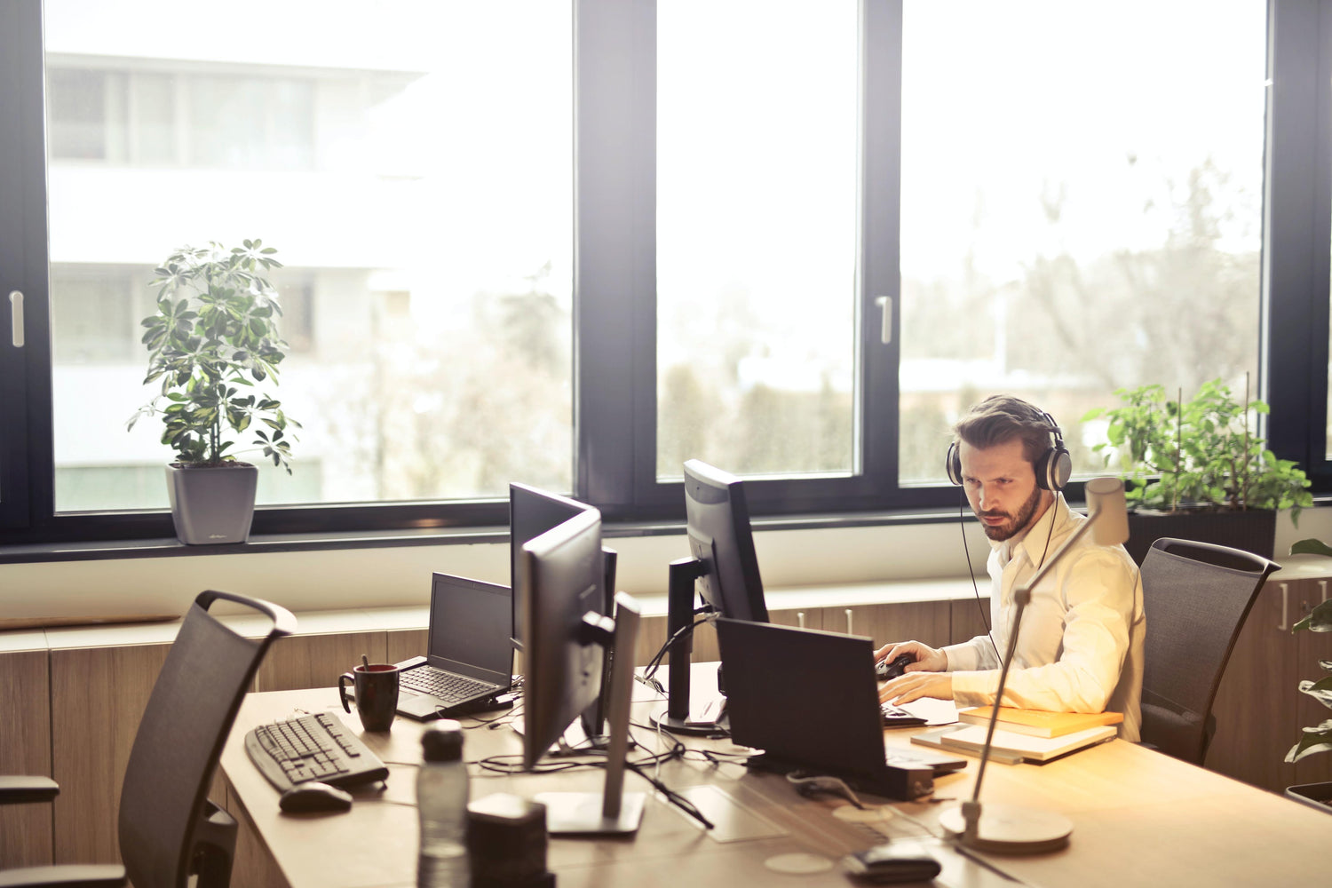 Man wearing headphone works intently on his computer at his desk